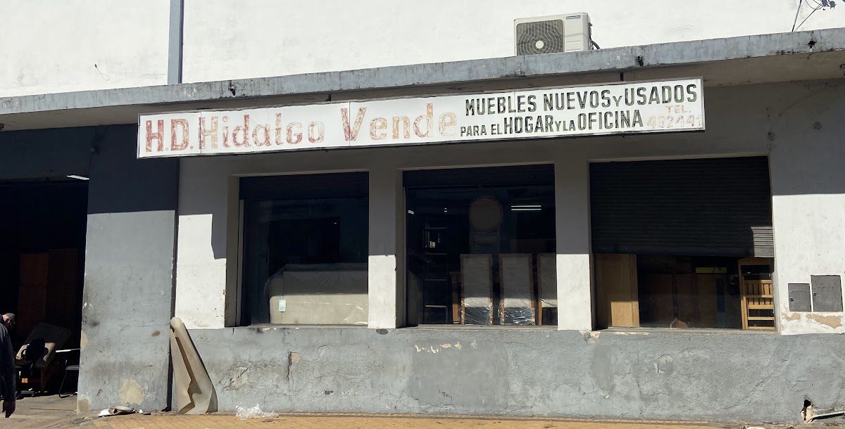 Vidrieras del local con sillas, un sillón y muebles de madera
