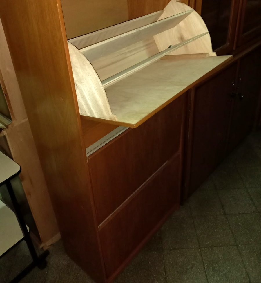 Zapatera de madera con tapa abatible junto a una vitrina
